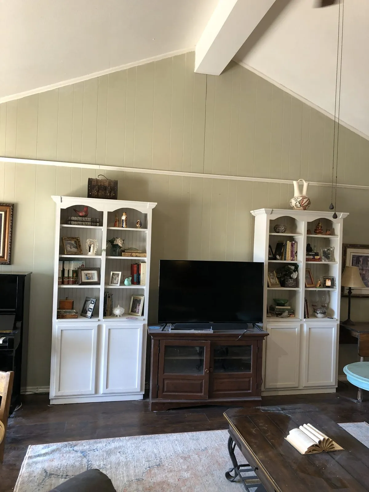 Living room with neutral walls, white built-ins, and a vaulted ceiling