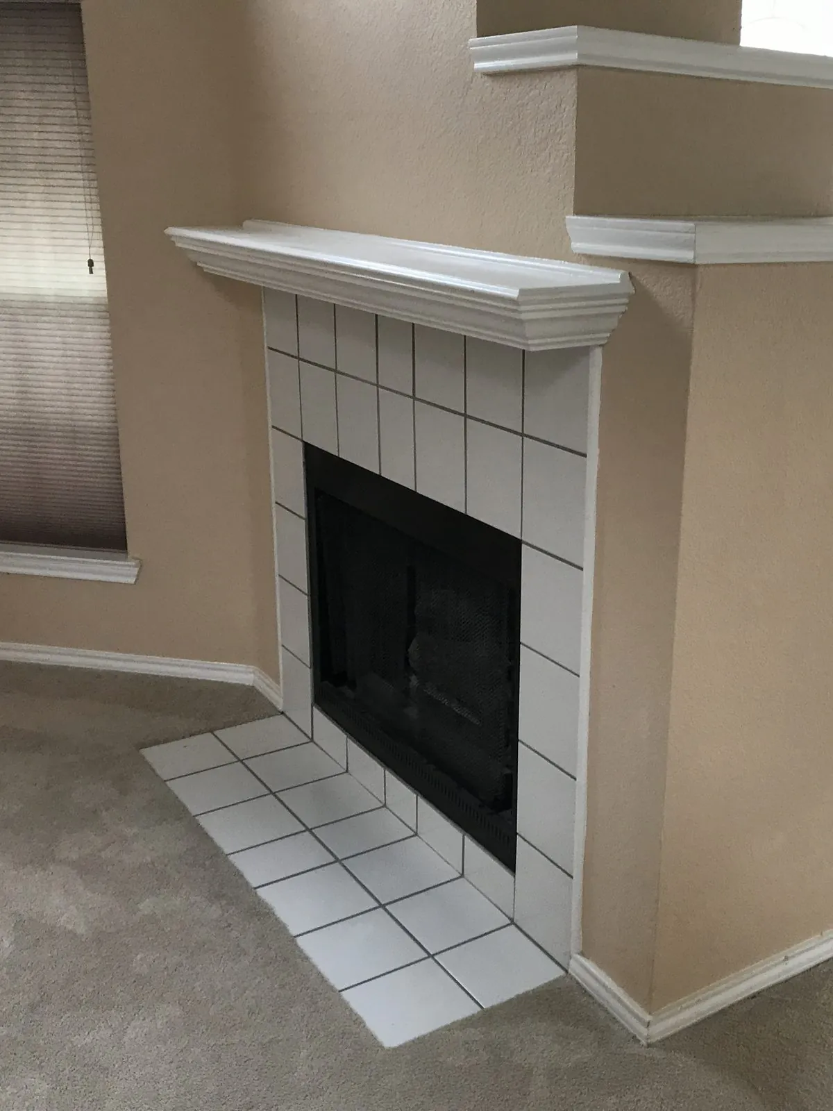 Empty living room with white trim, a fireplace mantel, and carpet